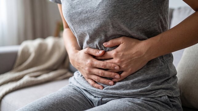 Woman suffering from severe stomach ache and menstrual cramps with red glowing pain area