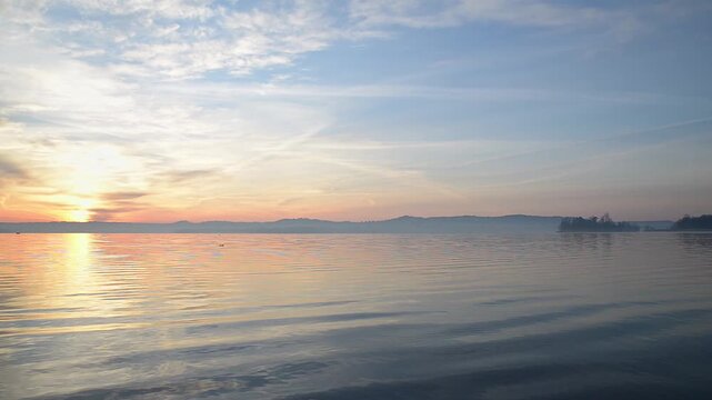 Sunrise over Lake Varese with calm water reflections and colorful dawn sky near Isolino Virginia UNESCO site in Biandronno, Lombardy, Italy