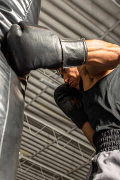 Powerful boxer punching heavy bag from low angle