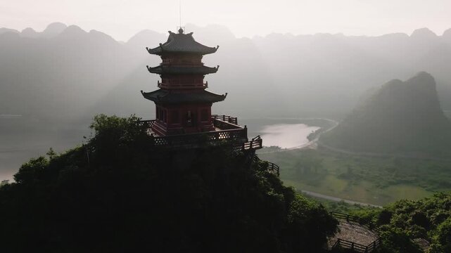 Aerial drone view of isolated pagoda on forested peak misty karst landscape Vietnam