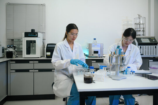 Two Female Scientists Working in Modern Research Laboratory with Equipment and Test Tubes