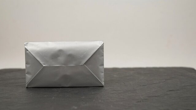 Folded silver thermal insulation mailing pouch mockup on dark slate background