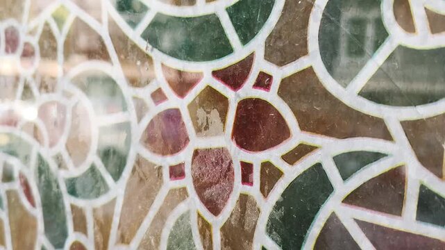 City life reflection on decorative mosaic glass window pattern. Elegant mosaic glass panel reflects urban street movement, creating abstract architectural background for modern design projects.