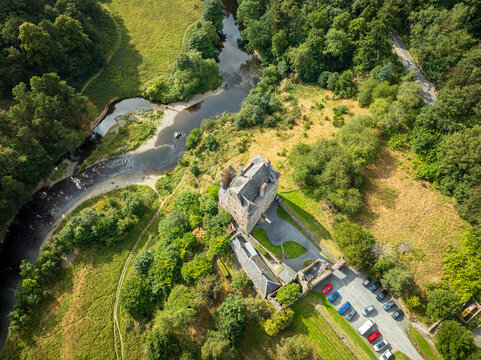 Aerial view of Neidpath Castle situated by the River Tweed, surrounded by lush green trees and meadows in Peebles, Scotland, United Kingdom.