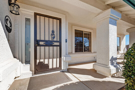 Front porch entry featuring stucco walls metal security gate arched sidelights and window front view
