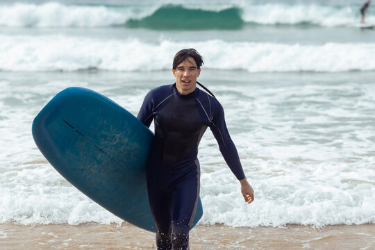Young man returns from surfing