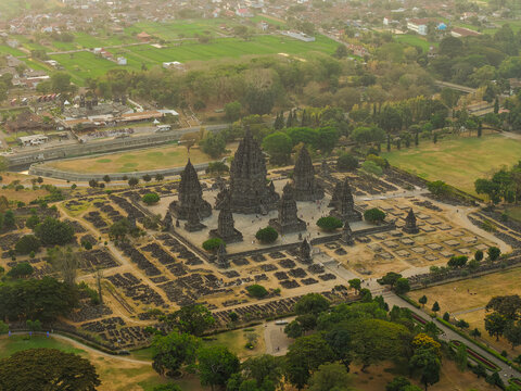 Aerial view of Prambanan Temple with its iconic stone spires and surrounding archaeological ruins set amidst lush green fields and trees in Yogyakarta, Special Region of Yogyakarta, Indonesia.