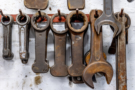 Rusty wrenches and industrial tools hanging on a workshop wall