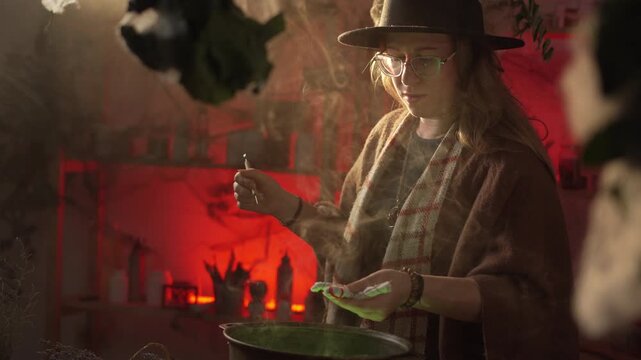 realistic witch brewing a potion. She holds a voodoo doll over the cauldron, pricks it with a needle, and recites a spell. Everyday life intertwined with traditional witchcraft. Magic and a mystical