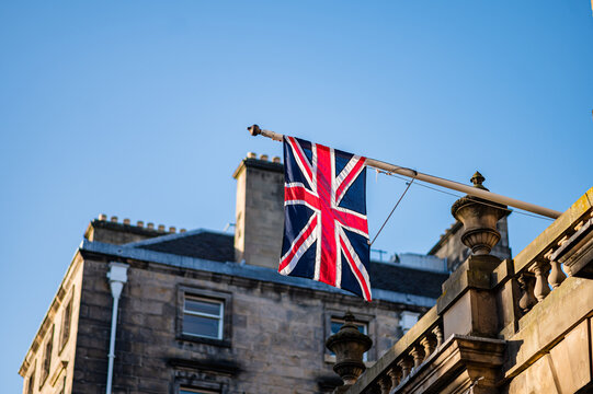 Union Jack flag above historic stone building under blue sky