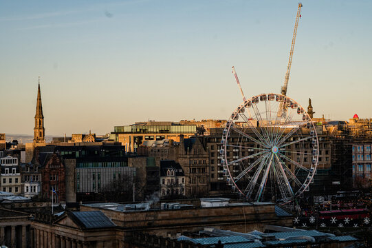 Ferris wheel above Edinburgh city buildings at sunset