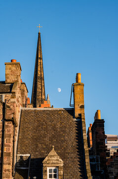 Edinburgh church spire above historic rooftops and moon