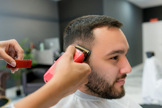 Barber trim man&rsquo;s hair with electric clipper in barbershop