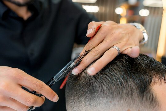 Barber cut man's hair with scissors in barbershop