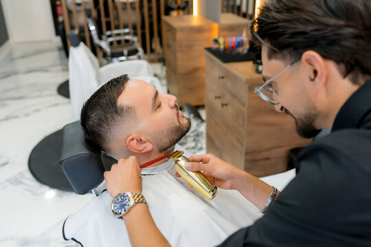 Barber trim beard with comb in modern barbershop