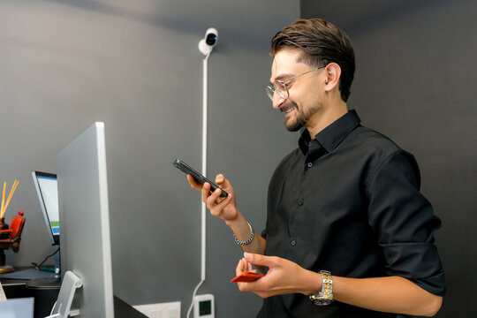 Barber use smartphone beside computer monitor in barbershop