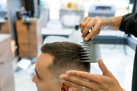 Barber use comb to style man's short haircut