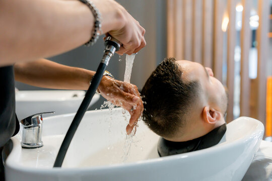 Barber check water temperature before hair rinse at wash basin