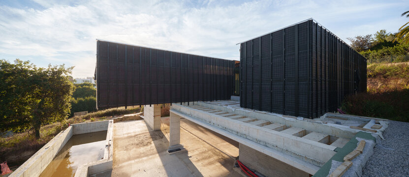 Modern house construction with black cladding and concrete foundation