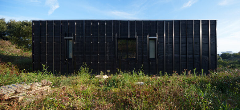 Black modern house under construction in rural landscape