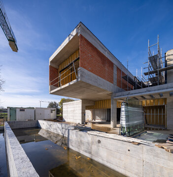 Modern house construction with concrete pool and brick facade
