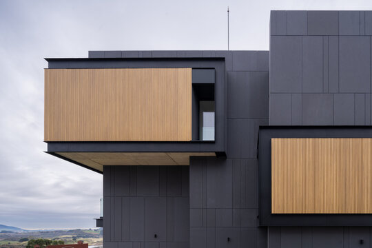 Modern hillside residence with dark facade and wood panels