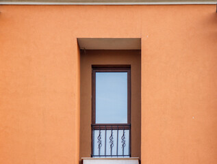 Fototapeta premium Minimalist modern window with wrought iron railing on orange plaster wall facade