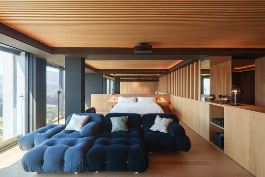 Modern coastal wooden bedroom with blue sofa and mountain view
