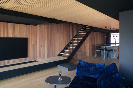 Modern coastal wooden interior with staircase and blue sofa