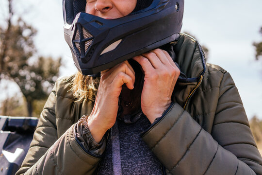 Woman fastens helmet before quad ride in nature