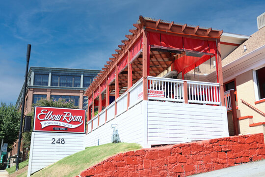 A brightly lit exterior shot of the front of Elbow Room, a classic local sports bar and neighborhood hangout located along Pharr Road NE near Peachtree Road in the Buckhead Village area of Atlanta, Ge