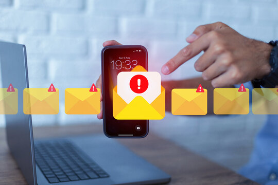 Man holding smartphone with email warning alert notification on screen. Concept of cybersecurity, phishing attack, spam mail, digital scam, and online threat warning in workplace.