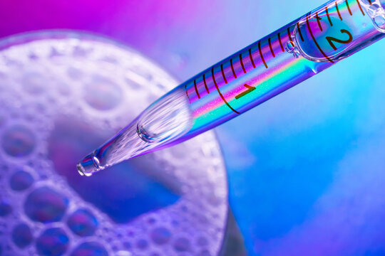 Macro pipette above petri dish in colorful science laboratory