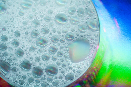 Macro view of petri dish with iridescent liquid droplets