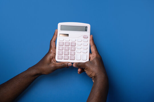 Black man hands holding calculator on blue background
