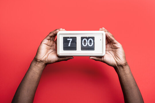 Black man hands hold flip clock at seven o'clock