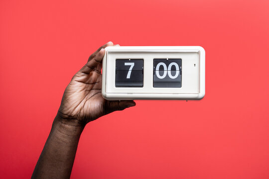 Black man hand holding retro flip clock at seven o'clock