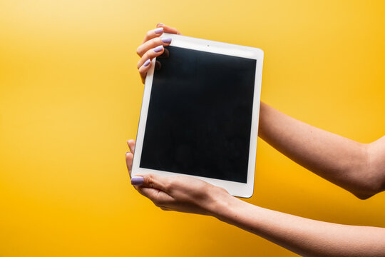 Woman hands hold blank tablet against yellow background