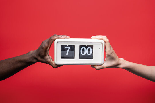 Diverse hands hold retro flip clock at seven o'clock