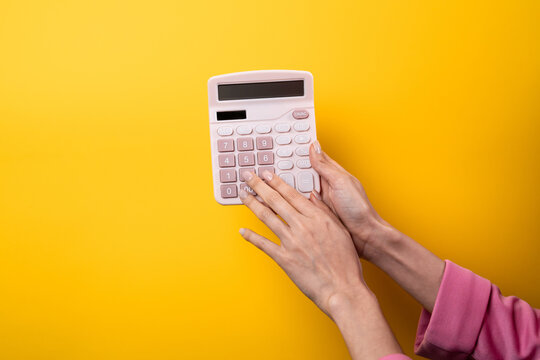 Woman using calculator against yellow background with copy space