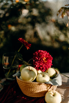 Autumn still life with apple, flower and woven basket