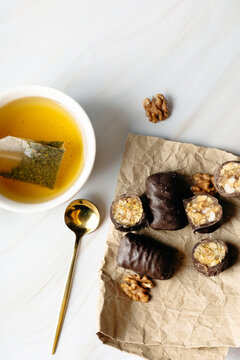 Herbal tea with chocolate sweet and walnut on table