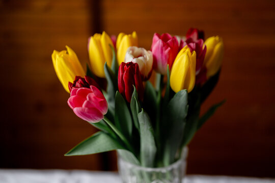 Colorful tulip bouquet in glass vase on wooden table