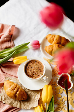 Coffee and croissant breakfast with tulips on table