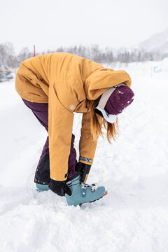 Woman fasten ski boot in snowy japan landscape