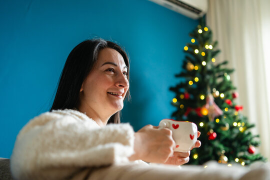 Woman enjoy Christmas at home with festive mug and tree