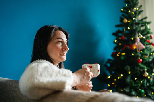 Woman enjoy Christmas at home with festive tree and mug