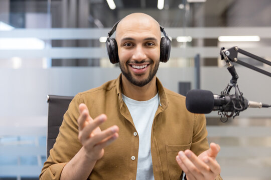 Podcast host recording audio content, smiling man with headphones and microphone talking to audience in studio, Professional communication and digital media production, influencer sharing information