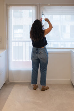 Woman adjust window blind in modern apartment interior
