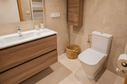 Modern apartment bathroom with vanity, toilet and wood cabinet